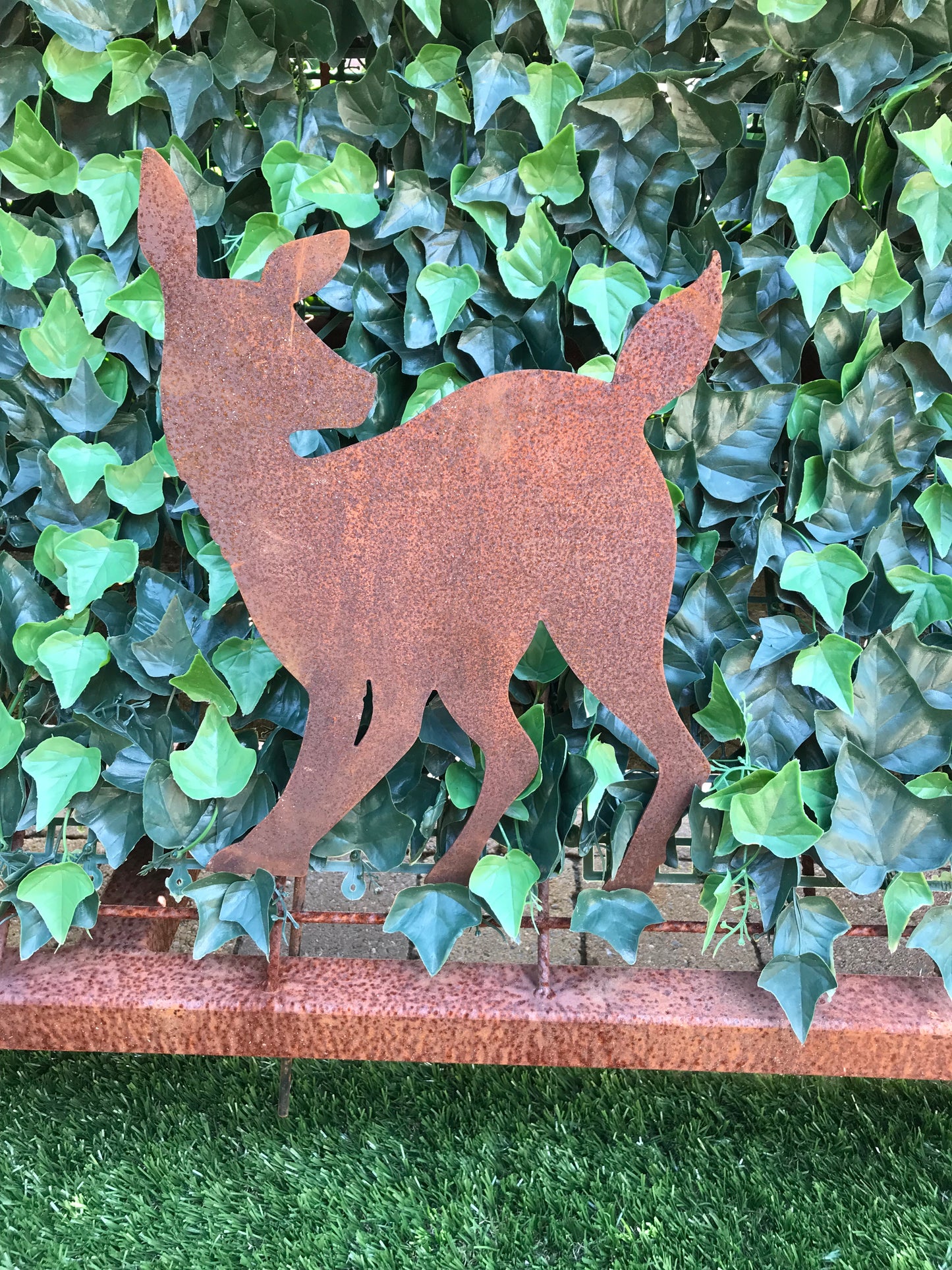 Jonge Ree achterom kijkend op tuinsteker